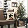 A festive Christmas scene with a decorated tree, a snowman pillow, and a plaid scarf draped over a wooden bench. Produktbild-Vorschau