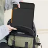 A person is placing a black laptop sleeve into a backpack. Náhled obrázku produktu