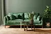 A green sofa in a living room with plants and coffee tables. Podgląd zdjęcia produktu
