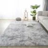 A fluffy gray rug in a living room setting with a sofa, plant, and decorative items. Náhled obrázku produktu