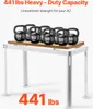 A white metal stand with a wooden top, loaded with several 50lb kettlebells to demonstrate its weight capacity. Produktbild-Vorschau