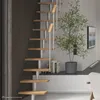 A modern interior with a spiral staircase, a potted plant, and a television on the wall. Produktbild-Vorschau