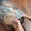 Hands are shown closing a vacuum seal bag filled with clothes. Náhľad obrázku produktu