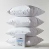 A stack of four white pillows with a product packaging insert in front of the bottom pillow. Produktbild-Vorschau
