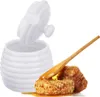 A white ceramic honey pot with its lid open, next to honeycomb and a wooden honey dipper. Náhled obrázku produktu