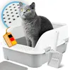 A gray cat sits in a white and gray litter box with a scoop and a mat nearby. A tag with German flag colors and text is attached to the litter box. Produktbild-Vorschau