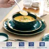 A hand is scooping soup from a bowl, which is part of a dinnerware set. Náhled obrázku produktu