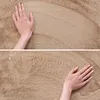 A close-up view of a hand touching a soft, beige carpet. Náhled obrázku produktu