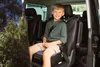 A young boy is sitting in a car seat in the back of a van. Produktbild-Vorschau