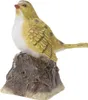 A decorative figurine of a yellow bird perched on a brown rock. Produktbild-Vorschau