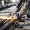 A person is using an angle grinder on train tracks. Náhľad obrázku produktu