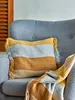 A striped throw pillow and blanket are placed on a gray armchair. Produktbild-Vorschau