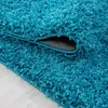 A close-up view of a teal shaggy rug, with a corner folded back to reveal the underside. Anteprima dell’immagine prodotto