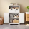A white bathroom cabinet with two doors and two drawers, filled with toiletries and towels, placed on a tiled floor. Produktbild-Vorschau