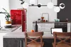 A modern kitchen with a red retro refrigerator, a kitchen island with chairs, and a laptop. Náhled obrázku produktu