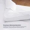 Weiße Matratzenauflage, die eine Matratze teilweise bedeckt, mit einer angehobenen Ecke, um die Passform zu zeigen Náhľad obrázku produktu