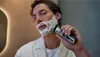 A man is shaving his face with an electric shaver. Anteprima dell’immagine prodotto