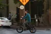 A man rides an electric bicycle across a street intersection. Anteprima dell’immagine prodotto