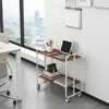 A rolling cart with two shelves is placed in an office setting next to a large window. Voir les images du produit