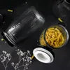 Two glass jars with lids, one filled with pasta, are arranged on a dark surface with dried flowers. Produktbild-Vorschau