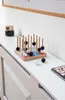 A wooden tic-tac-toe game with black and white pieces is displayed on a white surface next to a jar. Produktbild-Vorschau