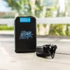 A black power bank with blue accents and a charger are placed on a wooden surface outdoors. Produktbild-Vorschau