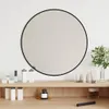 A round black-framed mirror is displayed above a wooden shelf with various cosmetic items. Anteprima dell’immagine prodotto