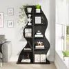 A black, wave-shaped bookshelf filled with decorative items and plants, placed next to a window with blinds. Podgląd zdjęcia produktu