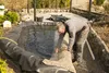 A man is installing a pond liner in a garden setting. Produktbild-Vorschau