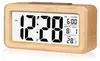 A digital alarm clock with a wooden frame and a white LCD display showing the time, date, alarm, and temperature. Produktbild-Vorschau