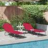 Two red lounge chairs are set up by a swimming pool on a patio, with a wooden fence and greenery in the background. Produktbild-Vorschau