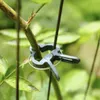 A close-up shot of green plant clips holding a plant stem and a thin support rod together. Voir les images du produit