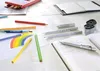 A collection of art and writing supplies, including pencils, colored pencils, a notebook, and a pencil sharpener, arranged on a white surface. Podgląd zdjęcia produktu