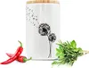 A white ceramic storage jar with a dandelion design, placed next to red chili peppers and a bundle of fresh herbs. Produktbild-Vorschau