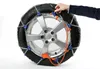 A person's hand is shown adjusting snow chains on a car tire and wheel. Produktbild-Vorschau