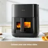 A black air fryer is shown on a countertop with a blurred background of a kitchen. Anteprima dell’immagine prodotto