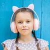 A young girl wearing cat-ear headphones against a blue wooden background. Náhľad obrázku produktu