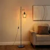 A floor lamp with a vintage industrial design is placed next to a chair in a room. Produktbild-Vorschau