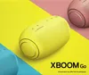 Three LG XBOOMGo Bluetooth speakers in different colors (yellow, pink, and blue) are arranged on a colorful background. Produktbild-Vorschau