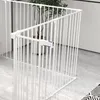 A white metal pet gate is set up in a room with a plant in the background. Produktbild-Vorschau