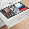 An open drawer filled with fabric storage organizers containing folded clothes, belts, and a wallet. Produktbild-Vorschau