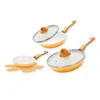 Three orange and white ceramic pans with glass lids and orange handles are arranged on a white background. One pan is on a flower-shaped orange trivet. Produktbild-Vorschau