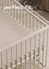 A close-up view of a crib with a fitted sheet, showing the texture and fit. Produktbild-Vorschau