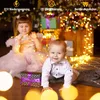 Two children are playing with Christmas lights around a Christmas tree. Voir les images du produit