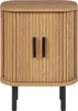 A front view of a light brown wooden nightstand with a ribbed texture and two black handles, standing on four black legs. Náhľad obrázku produktu