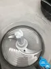 Close-up overhead view of the blades inside a clear food processor bowl. Produktbild-Vorschau