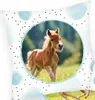 A close-up of a pillow with a foal in a circular frame, surrounded by polka dots and watercolor-like blue shapes. Produktbild-Vorschau
