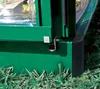 A close-up view of the base and corner of a green greenhouse structure, resting on grass. Podgląd zdjęcia produktu