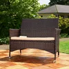 A brown rattan bench with a beige cushion sits on a wooden deck in a garden setting. Anteprima dell’immagine prodotto