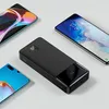 A black power bank is shown with three smartphones surrounding it on a light gray surface. Podgląd zdjęcia produktu
